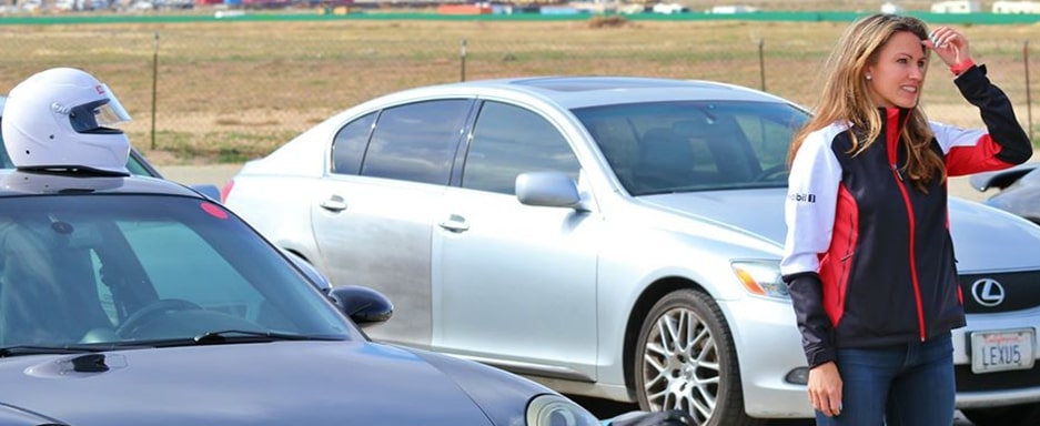 Photo of a woman surrounded by cars looking out into the distance.