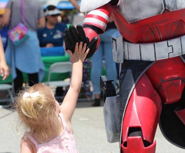 Photo of a little girl high-fiving a robot at a Willow Springs special event